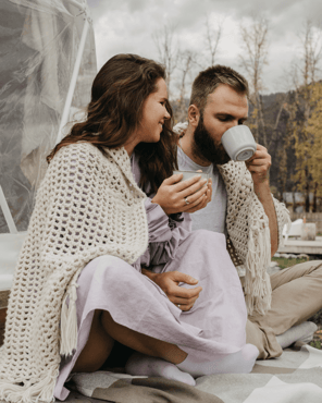 young-couple-outside-fall-day-cuddling-under-blanket-min