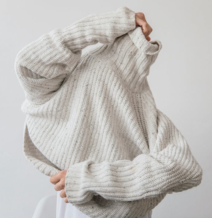 woman-putting-on-long-neck-knit-sweater